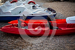 Red and white kayaks on the sand. Boats for leisure sailing laying on the beach. Kayak adventure trip. Extreme sports. Relaxing ti