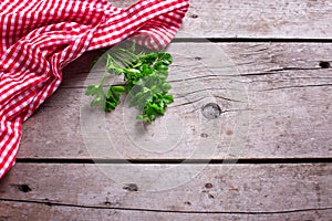 Red and white kitchen towel and green parsley leaves on rustic