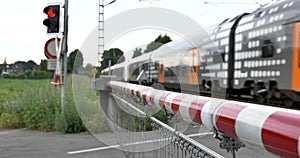 Red and white level crossing railway barrier which block the road and regional train.