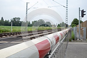Red and white level crossing railway barrier which block the road and regional train move on the railway.