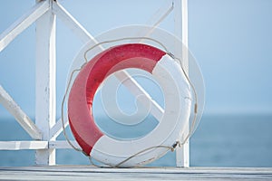 Red and white life bouy floater on wooden bridge on a sea side