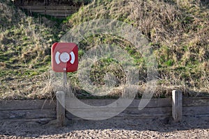 Red and white Lifebuoy on a beach