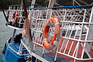 red and white lifebuoys on ropes hang on the metal fence of the ships