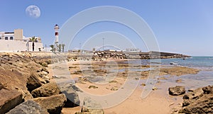 The red and white lighthouse of Rota. In the foreground the beach.