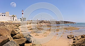 The red and white lighthouse of Rota. In the foreground the beach. photo