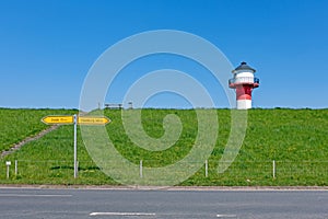 A red and white lighthouse towers over a dike in the Alte Land near LÃ¼he, Germany