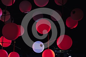 red and white modern pendant lamps, plastic spherical chandeliers. Illuminated lamp hanging against black background.