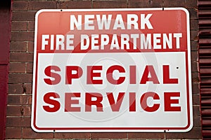 Red and White Newark Fire Department Special Service Sign Mounted on Brick Wall