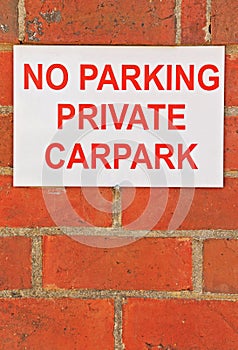 Red and white No Parking Private Carpark sign on brick wall