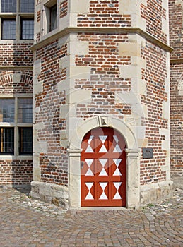 The red-white old door in the stoned wall