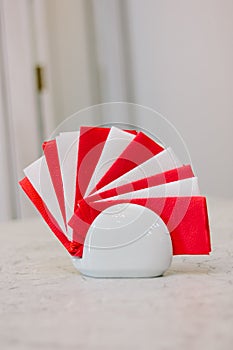 Red and white paper napkins in ceramic holder on table.