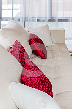 Red and white pillow on modern white sofa at home