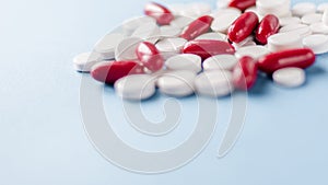 Red and white pills on the table. Closeup. Medical capsules. Medicine. Pharmaceuticals. Bioactive additives. Vitamins. Illness.