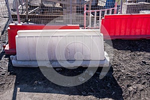 Red and white plastic barriers enclose a dug pit for construction and engineering work