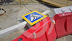 Red and white plastic road fences, road sign `Pedestrian crossing` and warning light