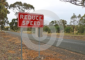 Red and white Reduce Speed safety sign on a country road