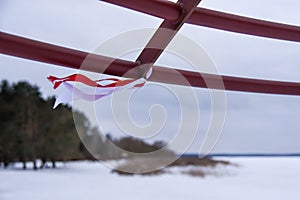 Red and white ribbons flutter in the wind in winter