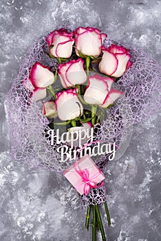 Red white rose flower bouquet with pink gift box on stone table.