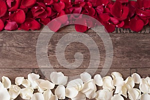 Red and white rose petals on the wooden background. Rose Petals Border on a wooden table. Top view, copy space. Floral frame.