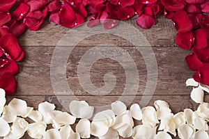 Red and white rose petals on the wooden background. Rose Petals Border on a wooden table. Top view, copy space. Floral frame.