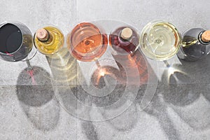 Red, white and rose wine in wine glasses and bottles with deep shadows on concrete background with copy space. Wines concept