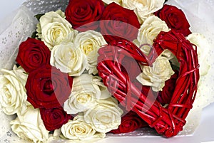 Red and white roses in a bouquet and a red heart from a vine. Valentine`s day background