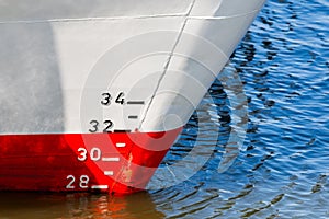 Red and white ship hull with waterline and draft scale measure
