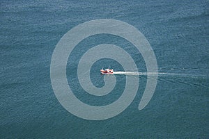 Red and white ship sailing alone in the vastness of the ocean seen from an elevated position. Concept coast, ocean, boats, fishing