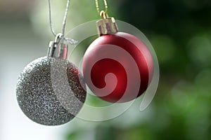 Red and white silver Christmas ball ornament hanging on a blur green tree bokeh light background. Christmas ornament background.