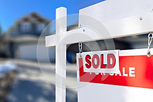 Red and white Sold sign in front of a house that is for sale and has recently been sold.