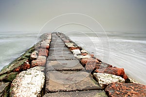 Red and white stone pier in the mist