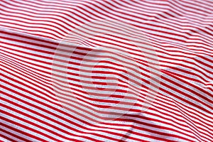 Red and white striped fabric texture. Crumpled bright colored cotton background. Selective focus. Closeup view