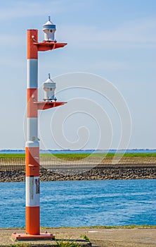 Red with white striped light pole at the harbor of Tholen, lamppost for the ships