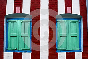 Red white striped wall with blue windows and green shutters, Yangon, Myanmar