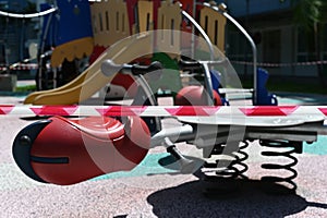 A red-white stripes barricade tape blocked off a children playground.