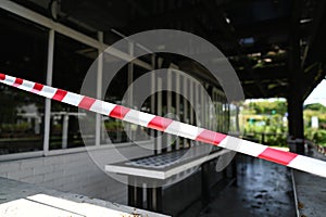 A red-white stripes barricade tape cordoned off a outdoor cafe.