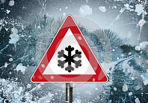 Red and white traffic sign with snowflake, caution winter tyres and winterreifen in front of a winterly scene