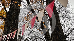 Red and white triangular bunting hanging against a background of bright yellow autumn foliage and sky