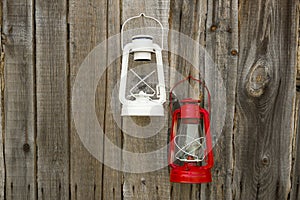 Red and white  vintage handle gas lanterns on rustic wooden wall.