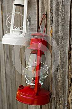 Red and white  vintage handle gas lanterns on rustic wooden wall.