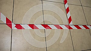 A red and white warning tape is affixed to the floor for social distancing