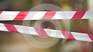 Red and white warning tape swinging in the wind. Protection sign. Don't cross the line. Red White caution tape pole