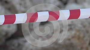 Red and white warning tape swinging in the wind. Protection sign. Don't cross the line. Red white caution tape pole