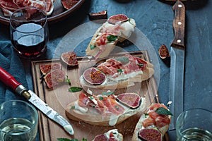 Red and white wine and bruschetta with bacon on a dinner table
