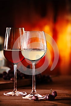 Red and white wine in front of a blazing fire