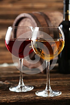 Red and white wine glass with bottle and barrel on a black background