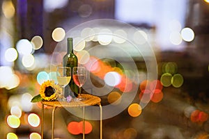 Red and white wine glass and bottle on table with blurry Beautiful glittering bokeh shine from car lights in traffic jam on city