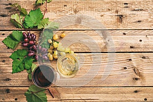Red and white wine glasses and fresh grapes on wooden background, copy space