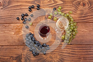 Red and white wine glasses and grape on wooden table