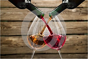 Red and white wine pouring in glasses on wooden